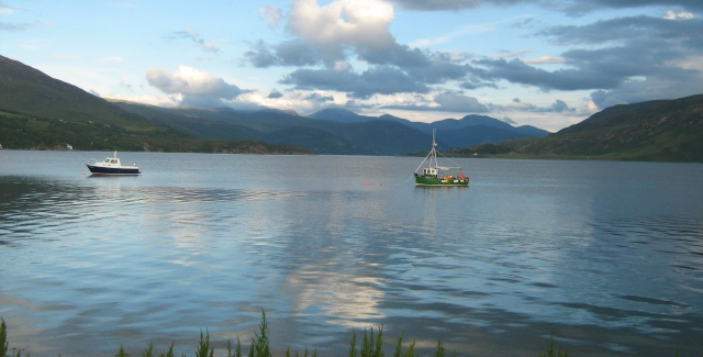 loch broom showing 2 small fishing boats on flat water with mountains in the background